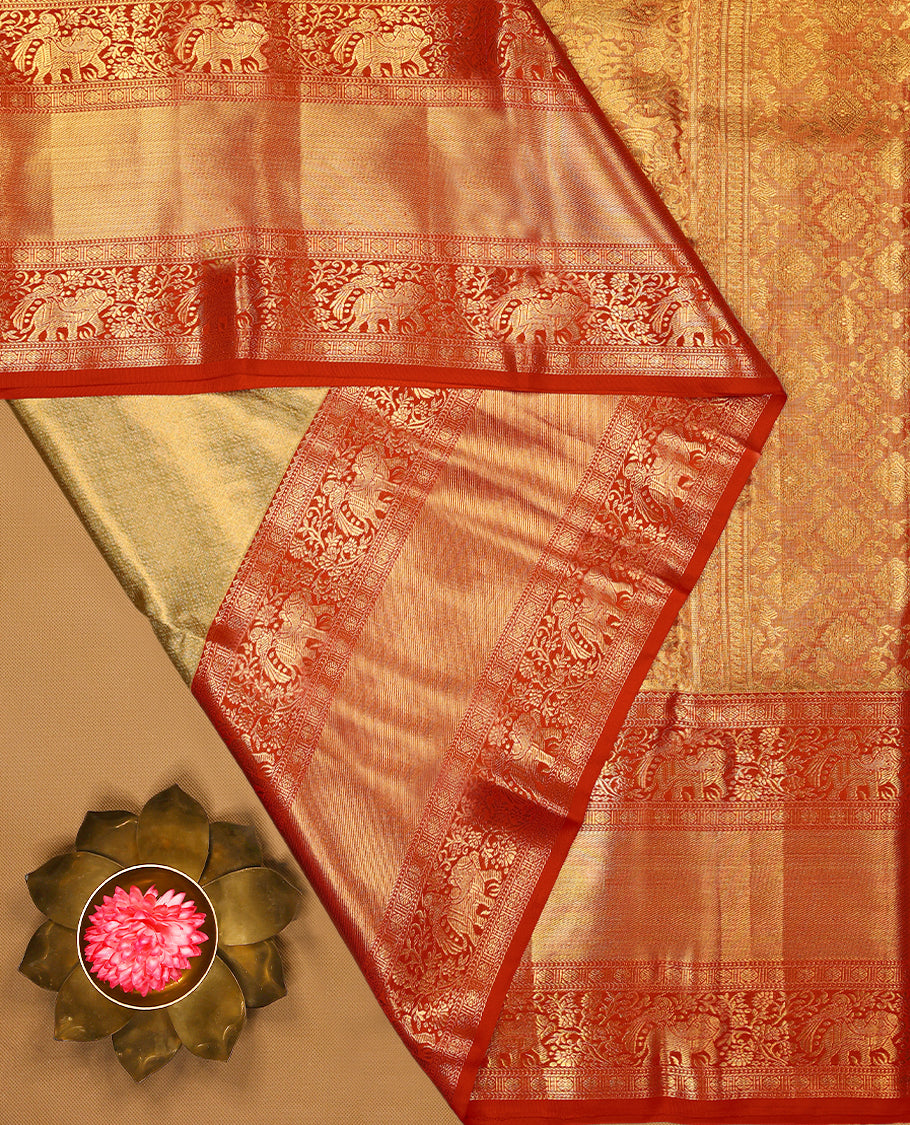 Gold Colour Kancheepuram tissue silk saree featuring an intricately woven antique zari jacquard design on the body, elegantly complemented by a bright red traditional border with elephant, bird, and Rudraksham motifs, and paired with a matching blouse.