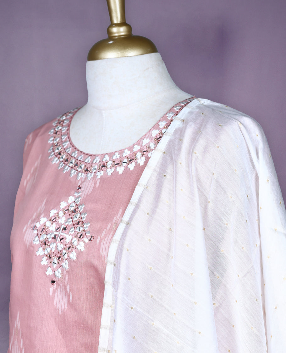 Dusty pink colour salwar set featuring ikat style motifs and delicate mirror work on the neckline, paired with matching plain bottom and an elegant off white dupatta with subtle golden thread detailing.