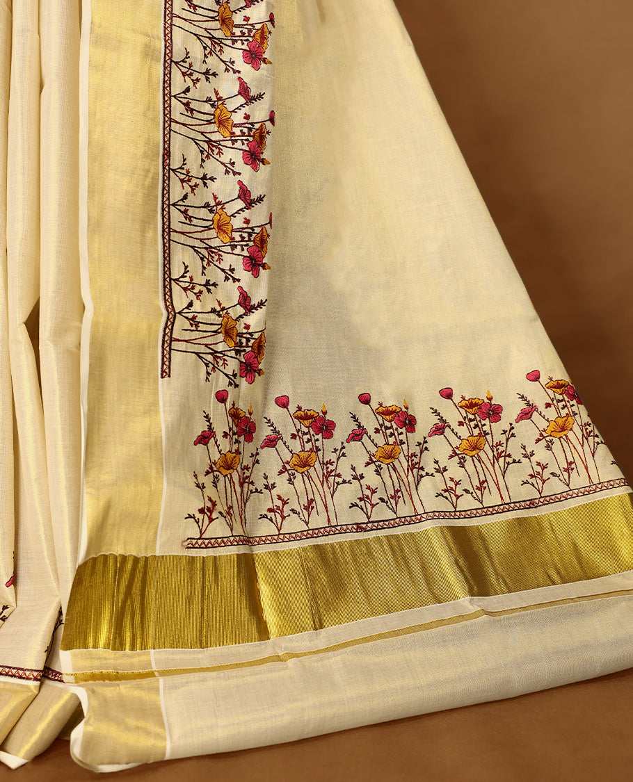 Light Gold colour Tissue Kerala saree featuring Plain body and a beautifully woven Gold Kasavu border with Heavy Floral embroidery work, paired with a matching blouse perfect for festive occasions.