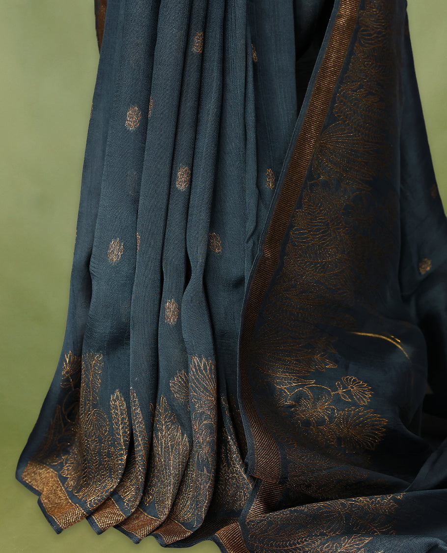 German blue semi-Banaras tussar georgette saree adorned with antique zari floral motifs on the body, beautifully highlighted with a pencil art garden-inspired border, paired with a matching blouse.