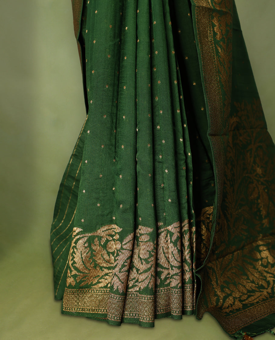 Bottle Green colour Tussar Banaras saree adorned with delicate golden zari motifs on the body, rich floral woven zari border and grand pallu, paired with a matching blouse for an elegant and regal traditional look.
