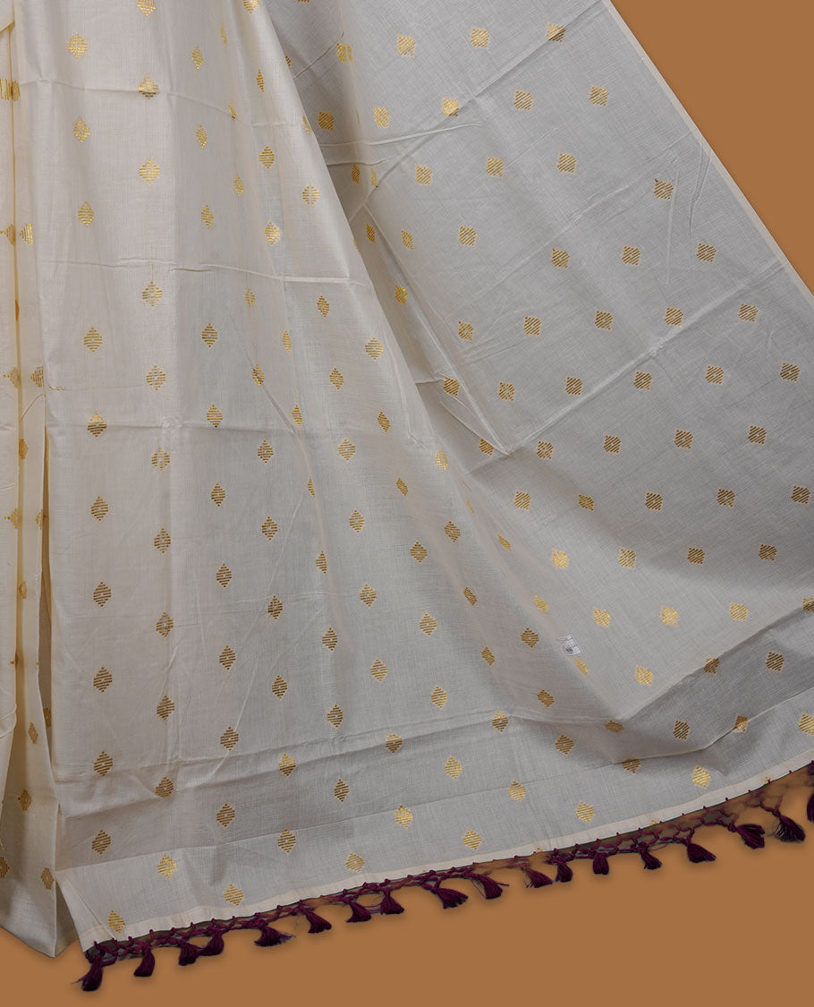 Off-white colour cotton Kerala saree featuring delicate gold butti motifs across the body and pallu, finished with a subtle gold border and tasselled pallu, paired with a matching blouse.