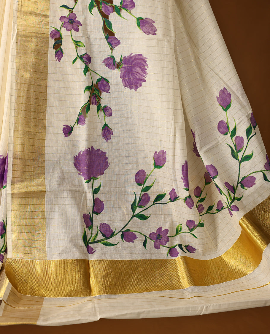 Elegant Off white colour cotton Kerala saree with hand-painted purple floral motifs, highlighted by a rich golden zari border and pallu paired with matching blouse.