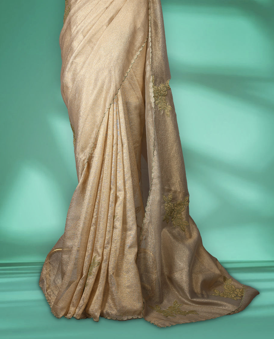 Beige gold colour organza designer saree featuring a subtle shimmer woven body with delicate green floral thread embroidery, scalloped thread detailing along the border and pallu paired with matching blouse.