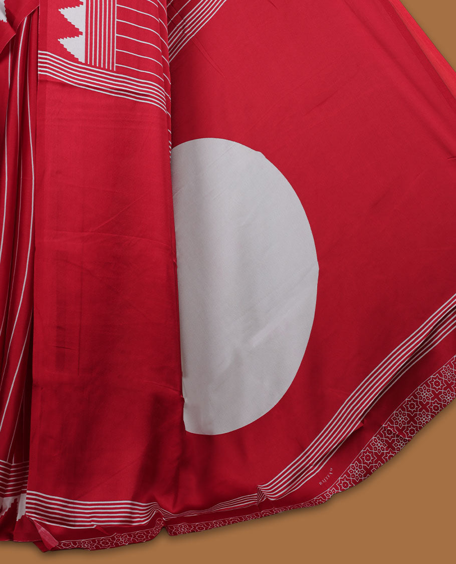 Red colour semi modal saree featuring white colour geometric borders and fine stripe detailing, finished with an oversized circular motif on the pallu, paired with a matching printed blouse.