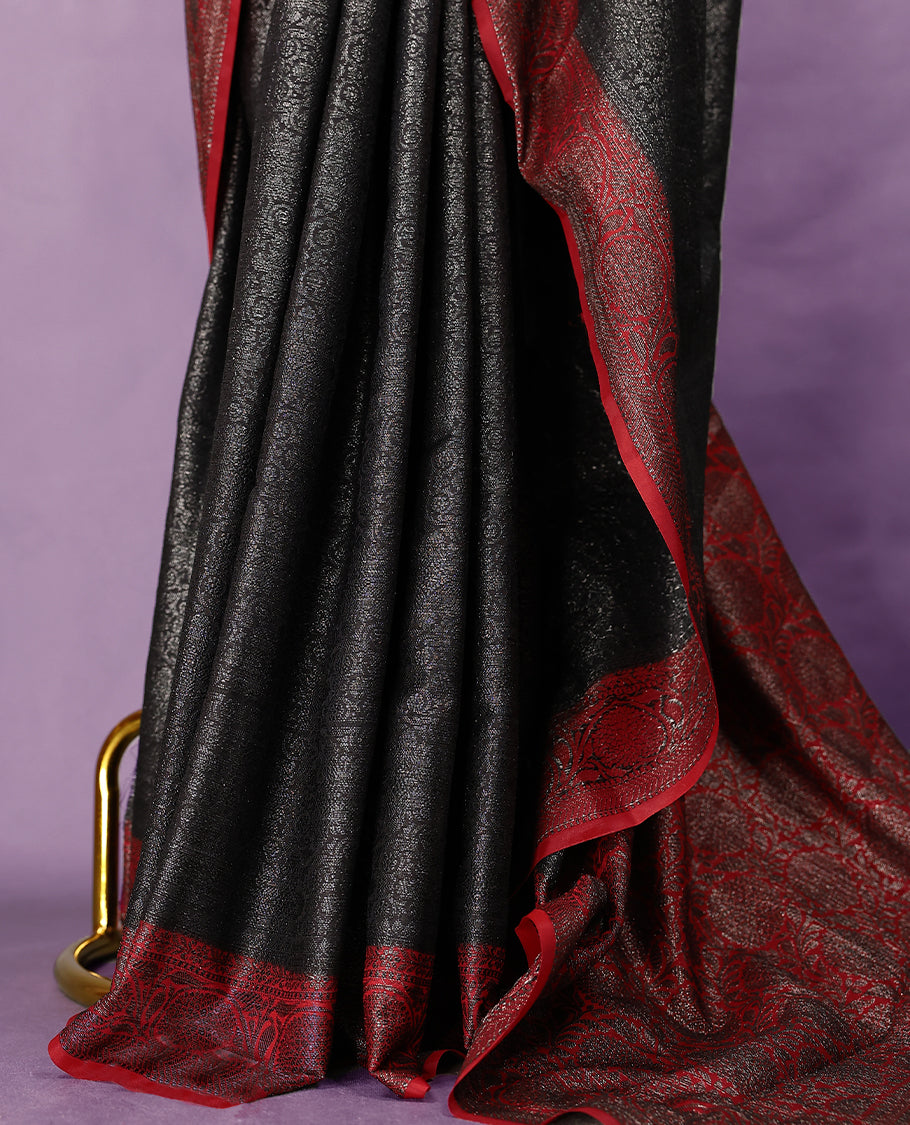 Black colour semi Banaras Katan saree featuring an antique zari jacquard body, complemented by a contrasting traditional border with a floral kodi design, paired with a matching blouse.
