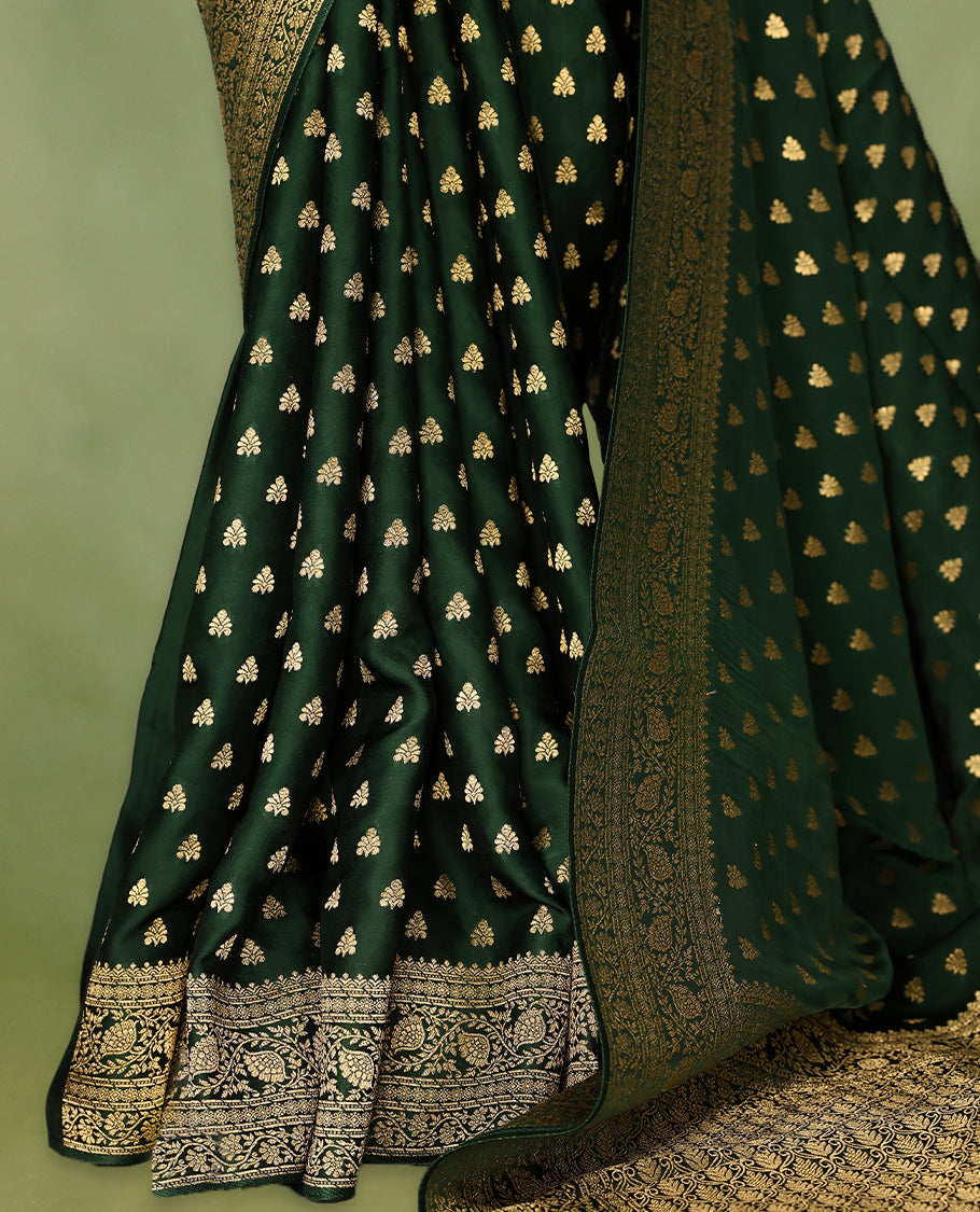 Bottle green semi-Banaras satin crepe saree featuring traditional closely woven buttas on the body, complemented by an antique-style border and a matching self-coloured blouse.