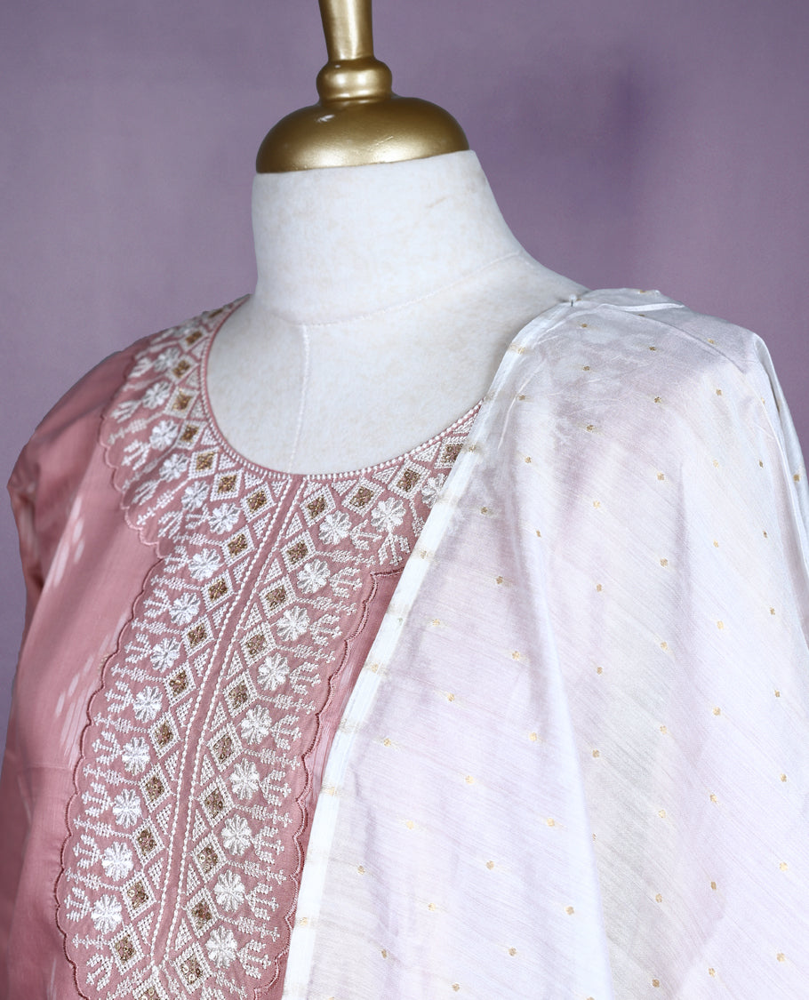 Dusty pink colour salwar set with ikat-inspired motifs and detailed mirror embroidery on the neckline, paired with plain bottom and an off white dupatta featuring golden striped detailing.