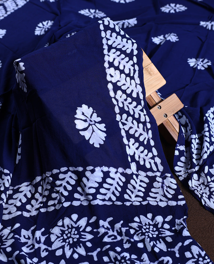 Navy blue colour churidhar material adorned with gold and copper toned floral patterns and bold block designs, paired with a plain matching bottom & Comes with a contrast dupatta featuring bold white leafy block prints.