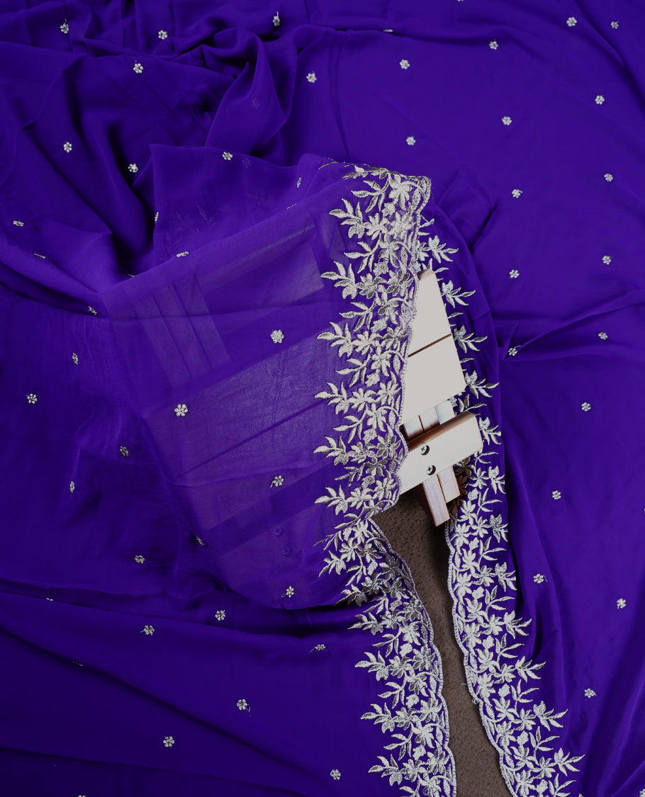 Indigo colour churidhar material adorned with silver floral embroidery and scattered butti work, complemented by a plain matching bottom and an elegant embroidered dupatta.