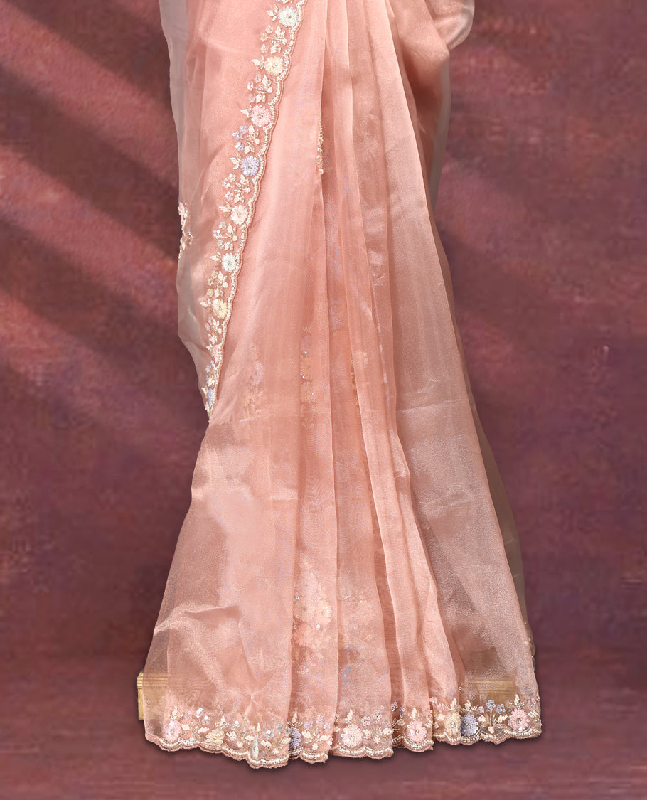 Peach colour pure organza saree featuring all over floral sequin work, adorned with a matching intricately worked floral border, complemented by a richly embellished pallu and paired with a heavily worked matching blouse.