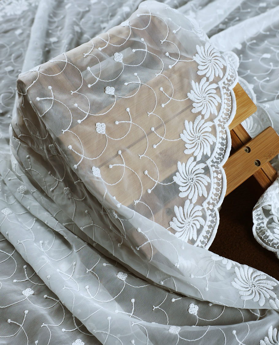 Elegant white colour churidhar material embellished with intricate floral embroidery and detailed thread patterns, paired with a plain matching bottom and embroidered dupatta, ideal for festive and elegant occasions.