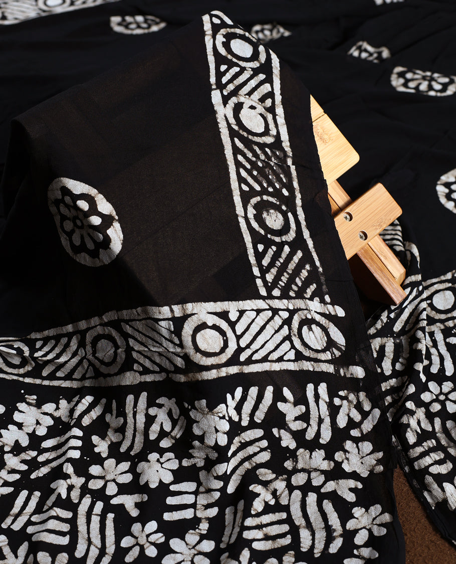 Black colour churidhar material adorned with gold and copper toned floral patterns and bold block designs, paired with a plain matching bottom and stylish dupatta, perfect for festive evenings and traditional gatherings.