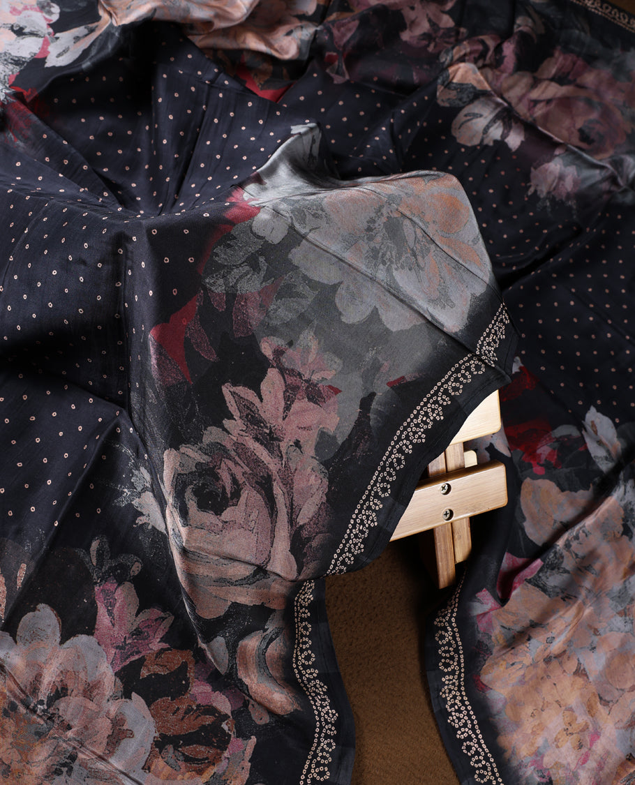 Black colour churidhar material highlighted with elegant zari embroidery on the neckline, paired with a plain matching bottom and a floral printed dupatta with dotted accents.
