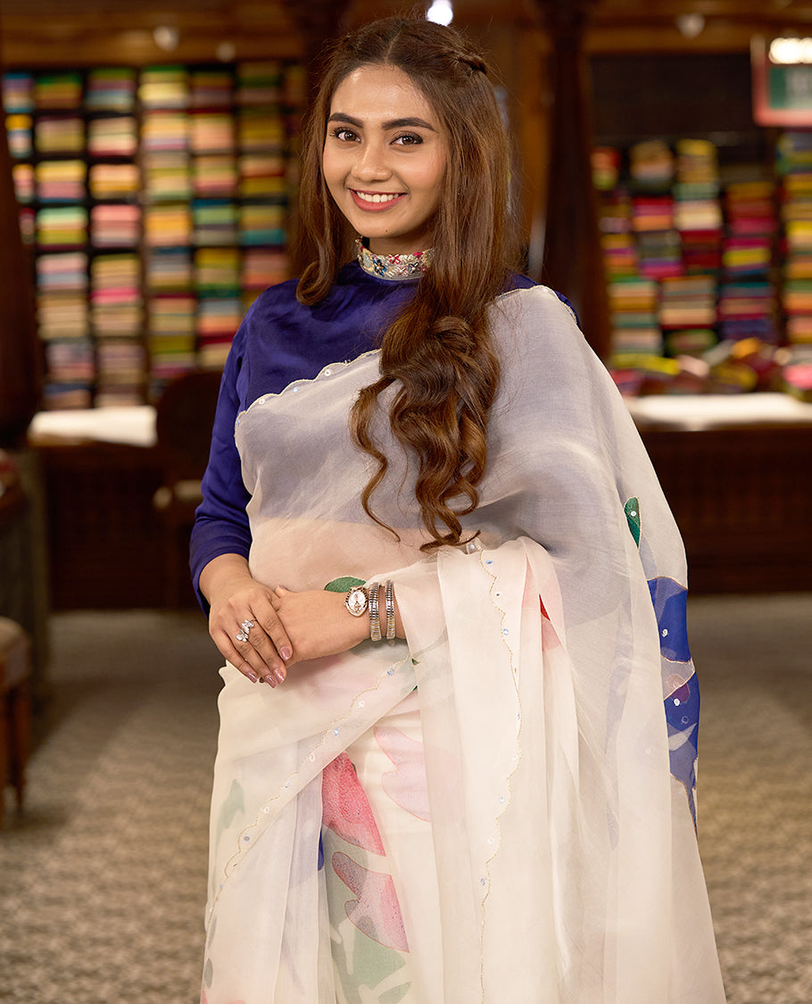 White colour pure organza silk saree featuring digitally printed fancy floral designs, adorned with delicate small mirror work, and finished with an elegant scalloped border, paired with a self colour crepe printed blouse