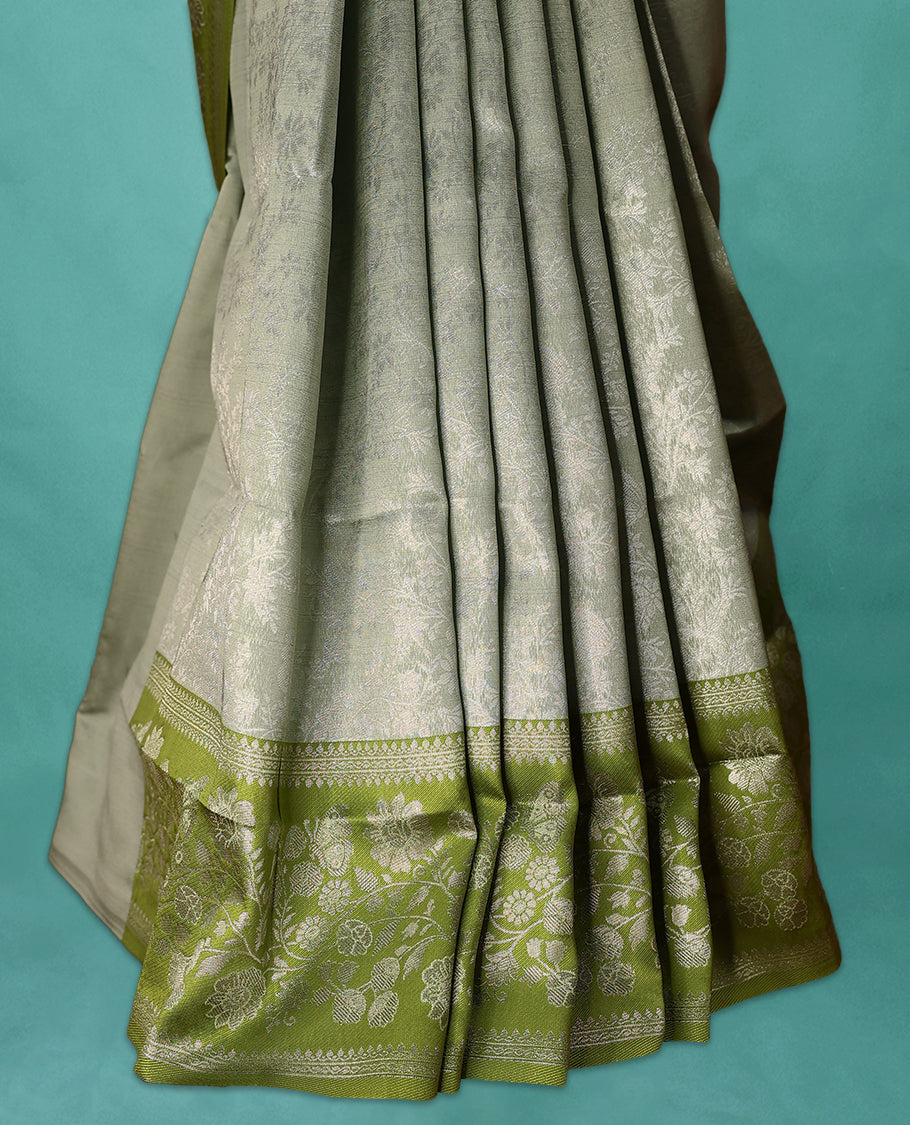 Light Pista coloured semi silk saree featuring a Silver coloured floral jaal design on the body, paired with a Green coloured border and matching blouse.