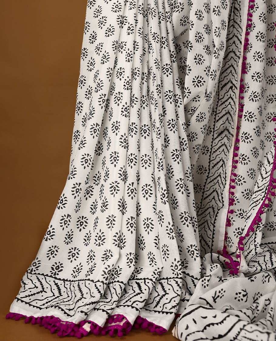 White cotton saree features intricate black handblock prints, a beautifully detailed border with pink piping and Self Coloured Blouse