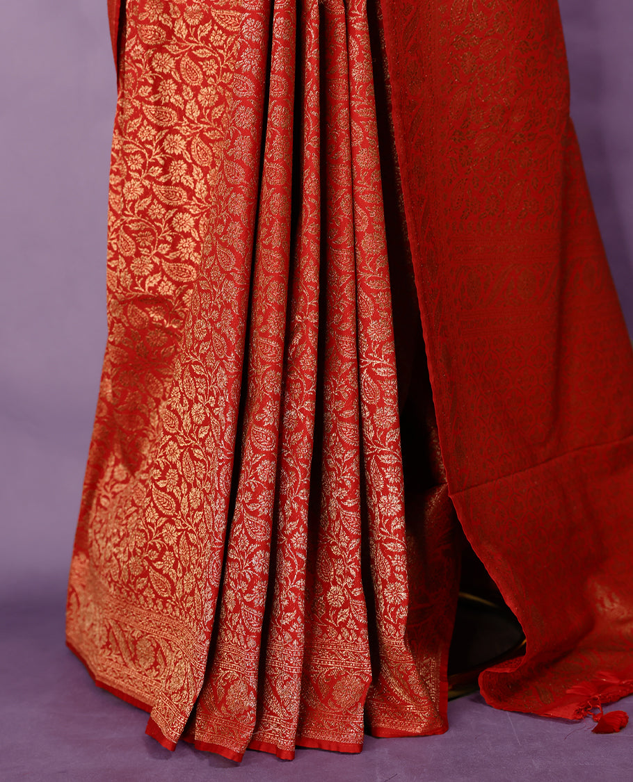 Chilli red colour semi Banaras Katan silk saree featuring intricate Antique Bronze zari floral and vine patterns woven throughout the body, enhanced with a rich traditional border and detailed pallu, paired with a matching blouse piece.