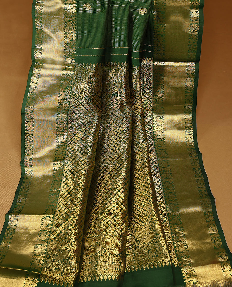 Bottle green Colour pure traditional Kancheepuramsilk saree featuring antique zari peacock and chakkram motifs on the body, complemented by a traditional border adorned with elephant and winged horse motifs, and paired with a matching Blouse