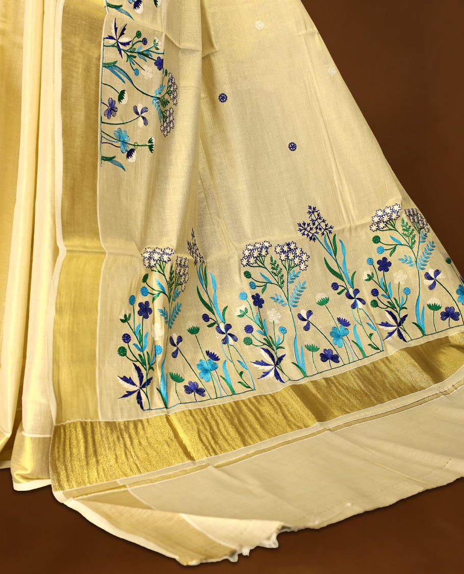 Light Gold colour Tissue Kerala saree featuring Blue and white Colour Floral thread work on body and a beautifully woven Gold Kasavu border, paired with a matching blouse perfect for festive occasions.