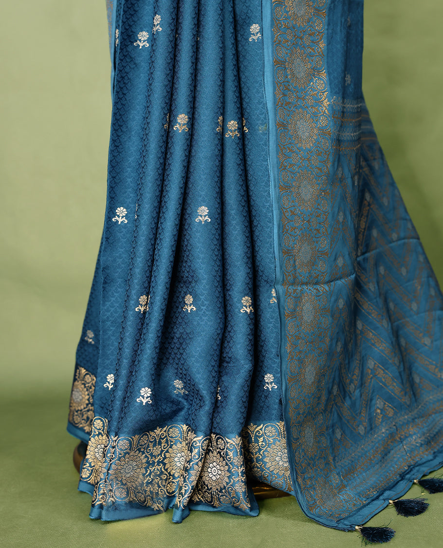 Blue colour pure Banaras crepe saree showcases elegant silver zari Flower Motifs all over the body, a traditional Banarasi gold zari border, a rich intricately woven pallu, and comes with a matching blouse.