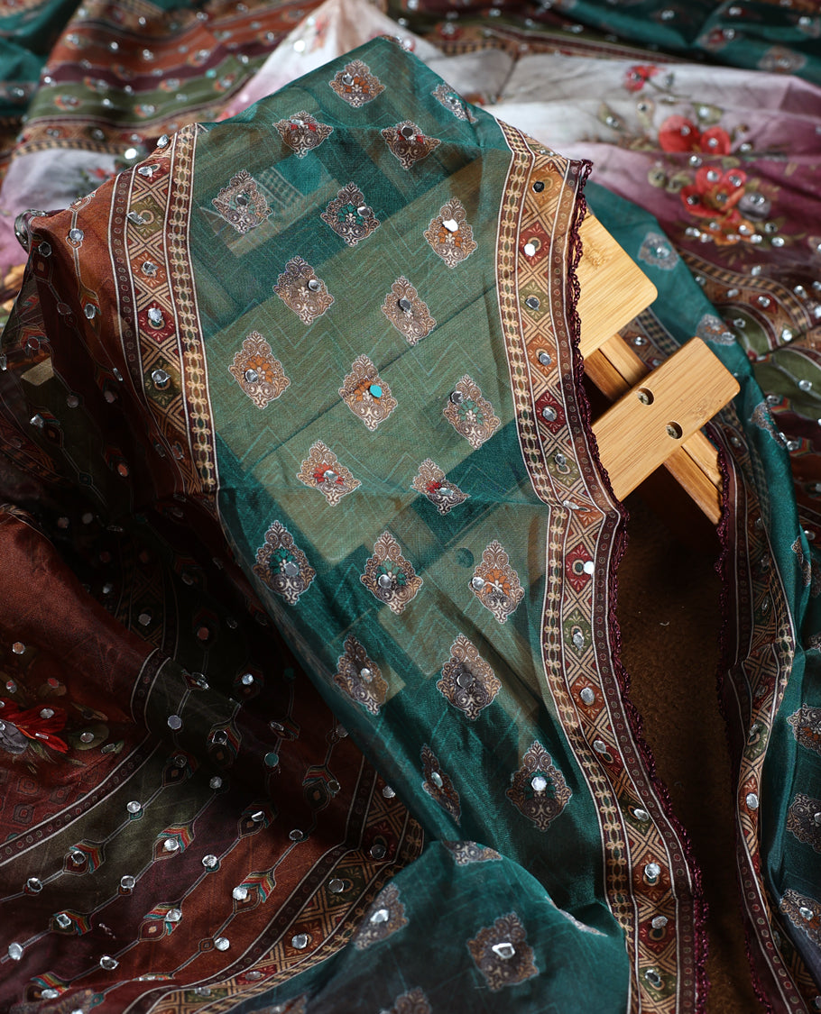 White colour churidhar material with mirror work and pastel floral prints, highlighted by earthy geometric borders & Comes with a plain white bottom and a dark green net dupatta adorned with shimmering mirror embellishments.