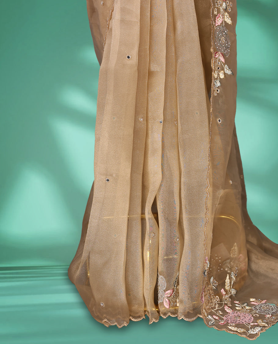 Dusty Pastel Brown colour organza saree featuring delicate floral embroidery with applique bead, mirror, and thread detailing on the body and scalloped border, lending a soft feminine charm, paired with a matching blouse.