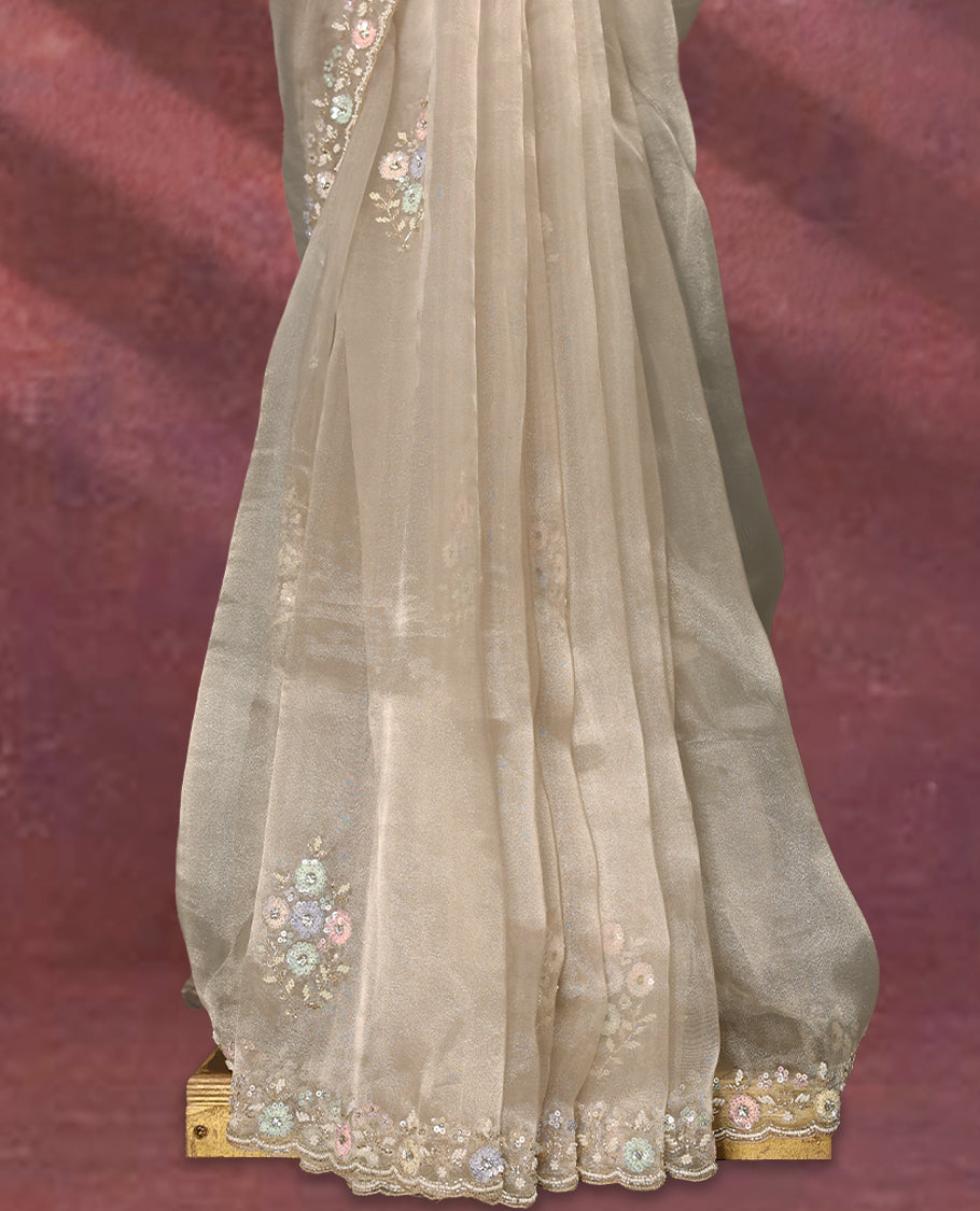 Deep beige colour pure organza saree featuring all over floral sequin work, adorned with a matching intricately worked floral border, complemented by a richly embellished pallu and paired with a heavily worked matching blouse.