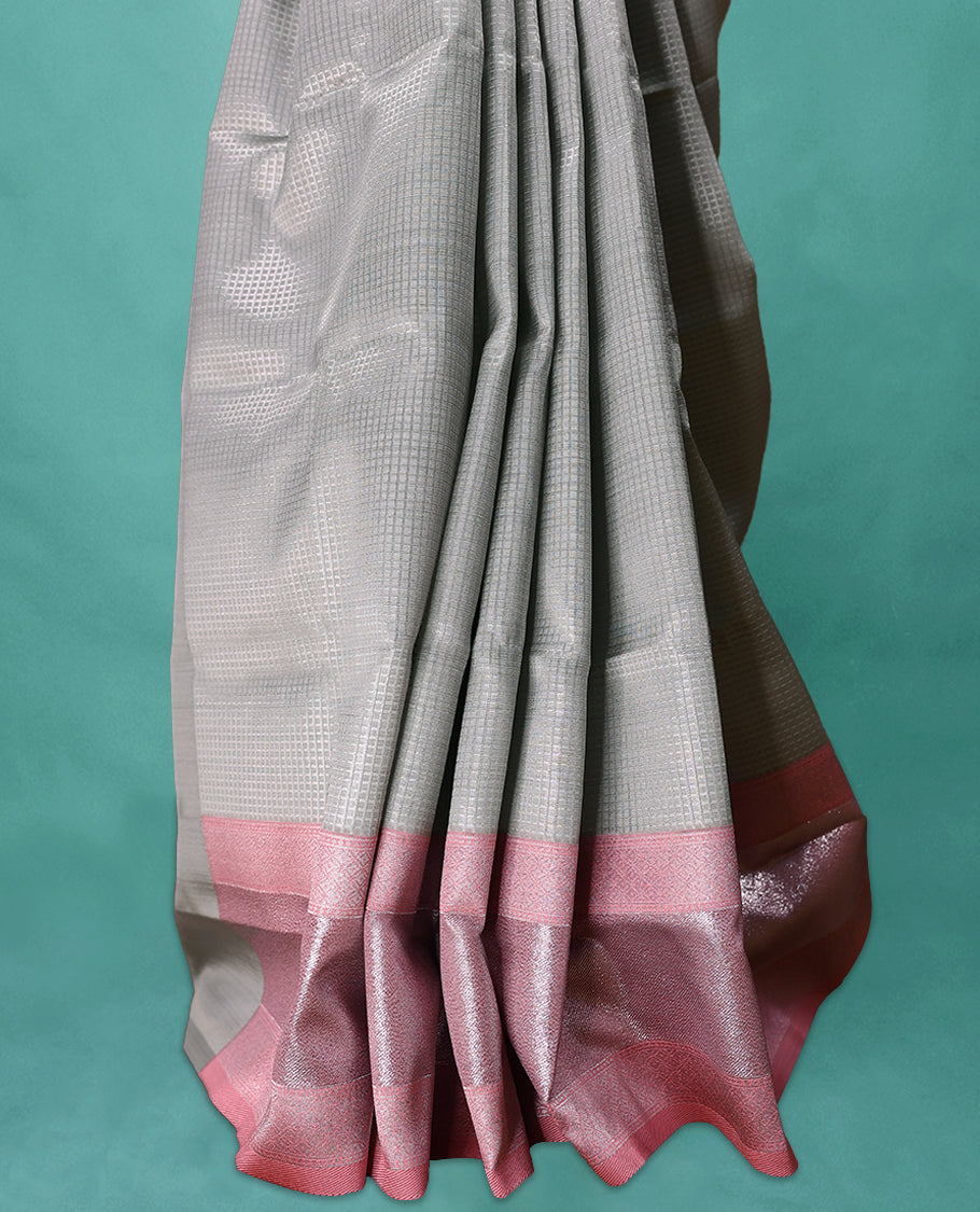 Silver coloured semi silk saree featuring a Self Coloured Check design on the body, paired with a Pastel Onion coloured border and matching blouse.