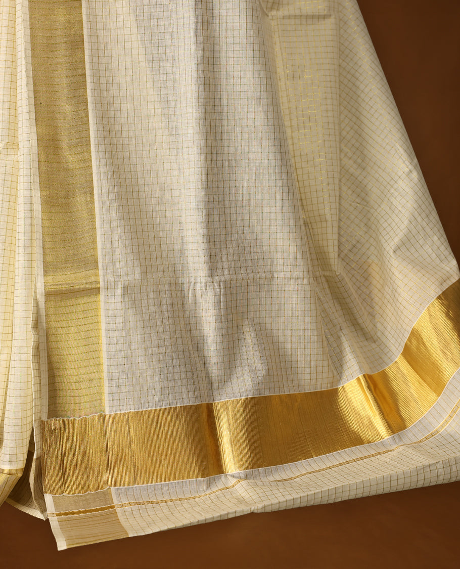 Elegant off white colour cotton Kerala saree with fine checkered patterns and a lustrous golden zari border, Paired with a matching blouse, it’s perfect for traditional functions and festive wear.