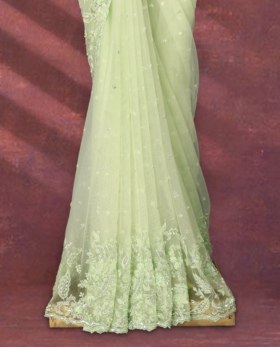 Pastel pistachio green colour net designer saree embellished with delicate floral thread and sequin embroidery along the border and pallu, with subtle sequin accents on the body, paired with a matching worked blouse for a refined look