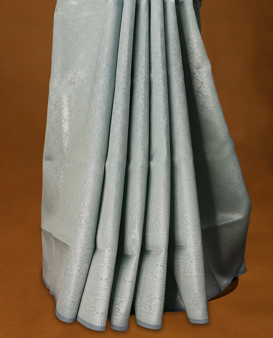 Pastel Grey coloured semi silk saree featuring a Silver coloured Zari Diamond design on the body, paired with a Self coloured border and matching blouse.