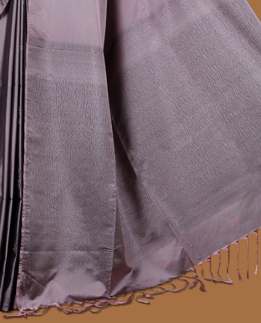 Pinkish gray colour semi soft silk saree adorned with delicate woven floral kodi motifs on the body, complemented by a Self colour woven pallu with intricate detailing and tassel accents without border & Comes with a matching blouse piece.