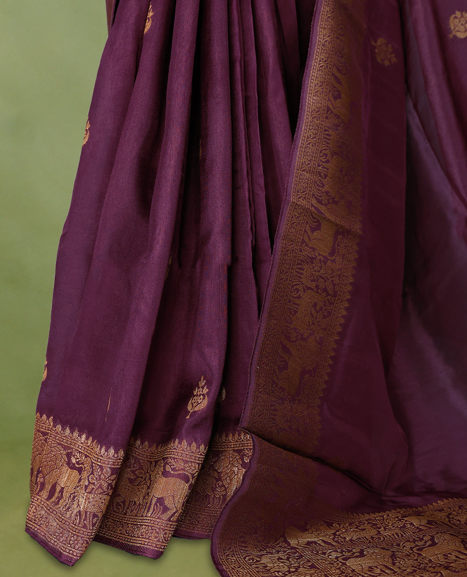 Light black currant semi Banaras tussar georgette saree adorned with antique zari butta motifs on the body, accentuated by a beautifully crafted jungle themed border, and paired with a matching blouse.