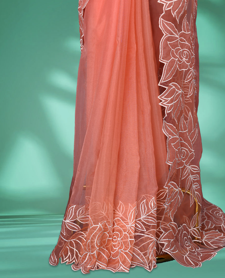 Peach colour net organza exclusive designer saree featuring a plain body and a beautifully adorned border with applique and thread embroidery work, complemented by a rich pallu and paired with a matching blouse
