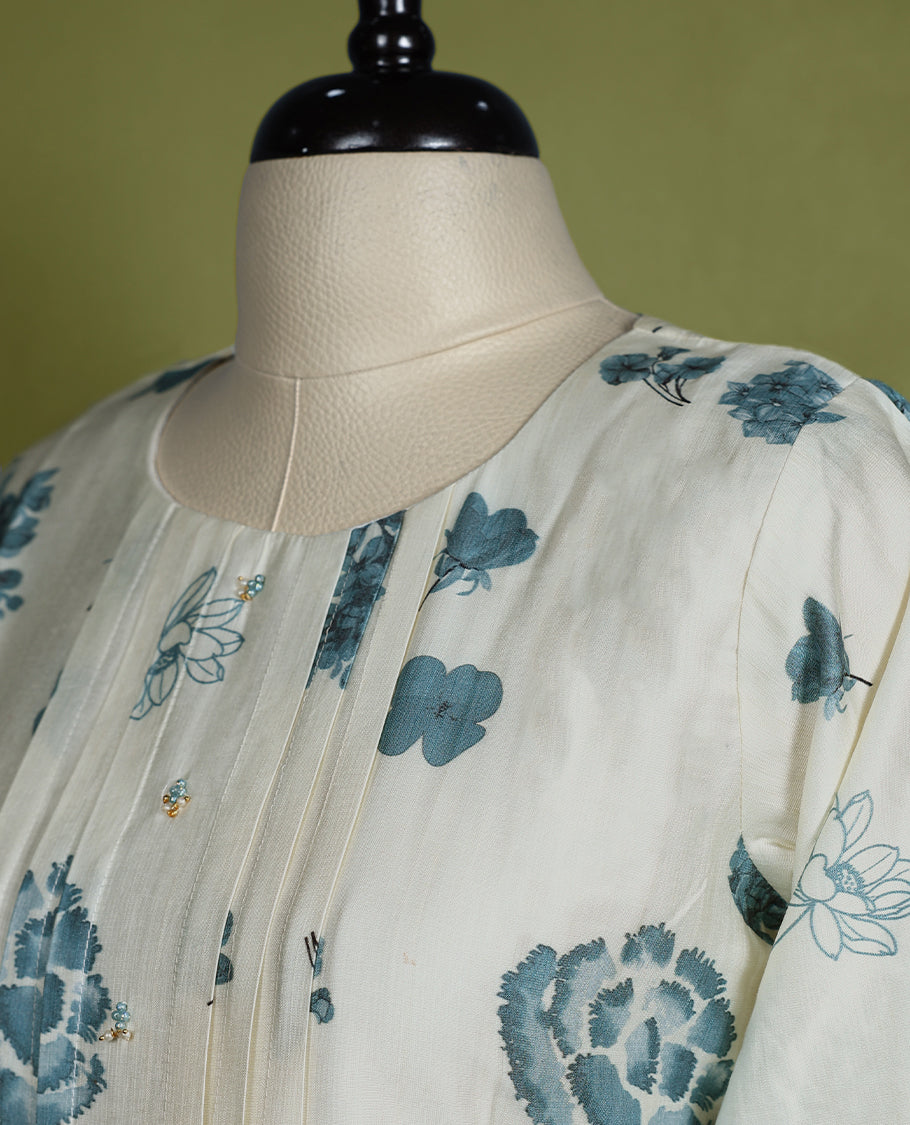 Off-white colour cotton kurti with blue floral prints, ombre dyed three quarter sleeves and hem, featuring a round neckline with a slight slit and front pintuck detailing
