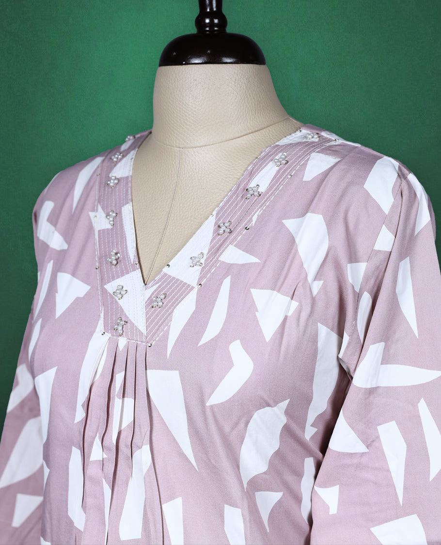 Pastel pink colour kurti featuring white tribalinspired geometric prints, styled with a V neckline adorned with subtle thread embroidery and 3/4th sleeves ideal for a contemporary ethnic look.