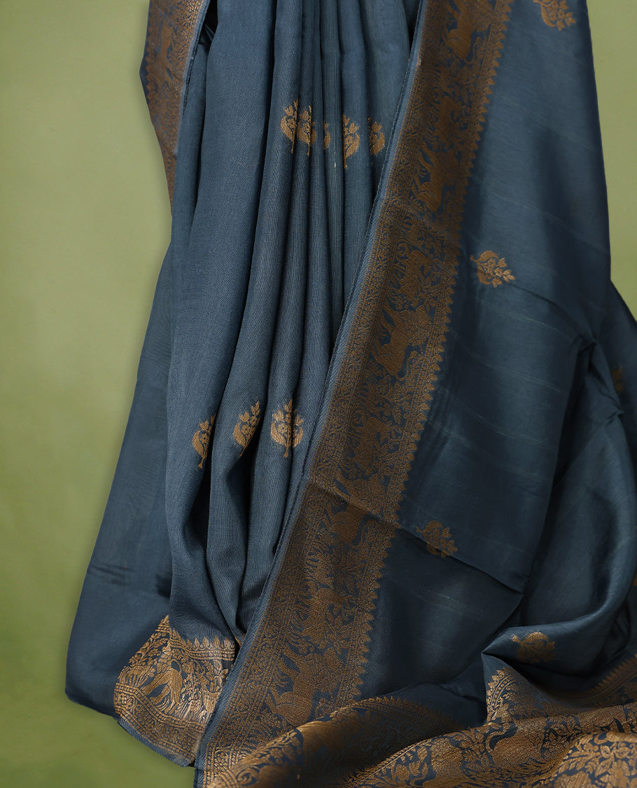 German Blue semi-Banaras tussar georgette saree adorned with antique zari butta motifs on the body, accentuated by a beautifully crafted jungle-themed border, and paired with a matching blouse.