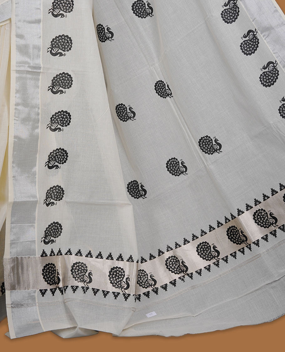 Off-white colour cotton Kerala saree featuring a subtle silver kasavu border, adorned with classic black peacock motifs across the body and pallu, and paired with a matching blouse.