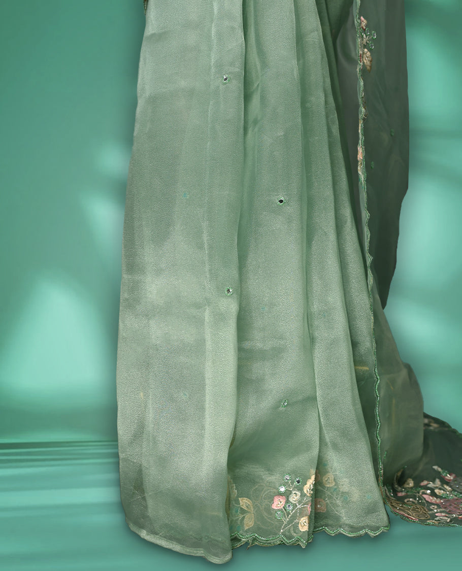 Pastel Green Colour organza saree featuring delicate floral embroidery with applique, bead, mirror, and thread detailing on the body and scalloped border, lending a soft feminine charm, paired with a matching blouse.