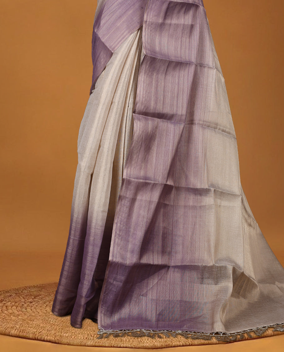 Beige and Lavender colour saree featuring a subtle woven texture & The shaded lavender pallu adds a graceful charm & Finished with delicate tassels and paired with a matching blouse piece.