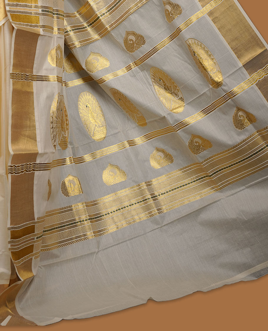 Off-white cotton Kerala saree featuring gold zari buttas, a broad kasavu border, and a traditional pallu, paired with a matching blouse.