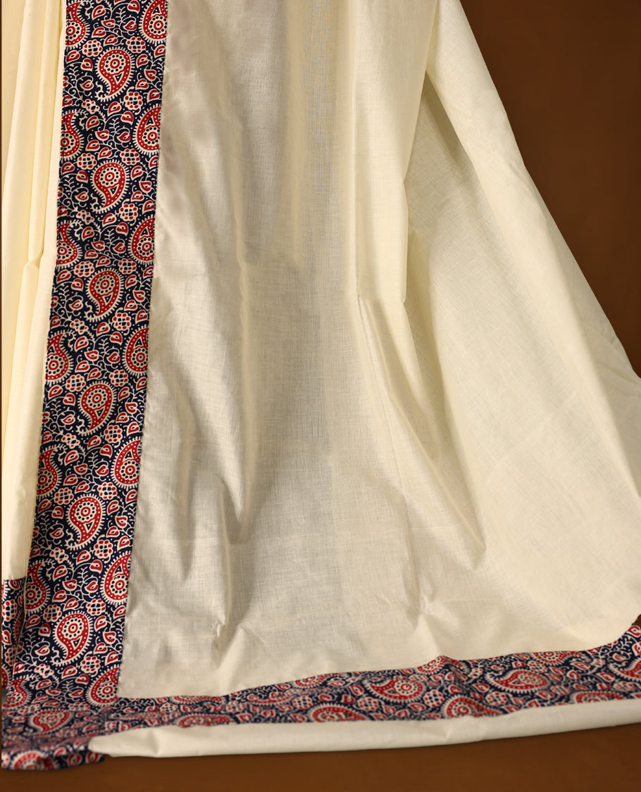 Off white colour cotton Kerala saree featuring a navy blue border with red and white paisley prints, paired with a matching printed blouse for a traditional yet vibrant look