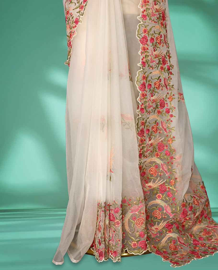 Off white colour organza saree featuring delicate floral and bird themed embroidery with scalloped edges on the border and pallu, lending a graceful charm. Paired with a matching blouse.
