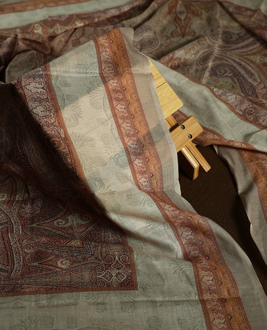 Beige colour churidhar material with subtle paisley motifs, sequin highlights, and woven border design, paired with a plain matching bottom and a soft printed dupatta for a graceful ethnic look.