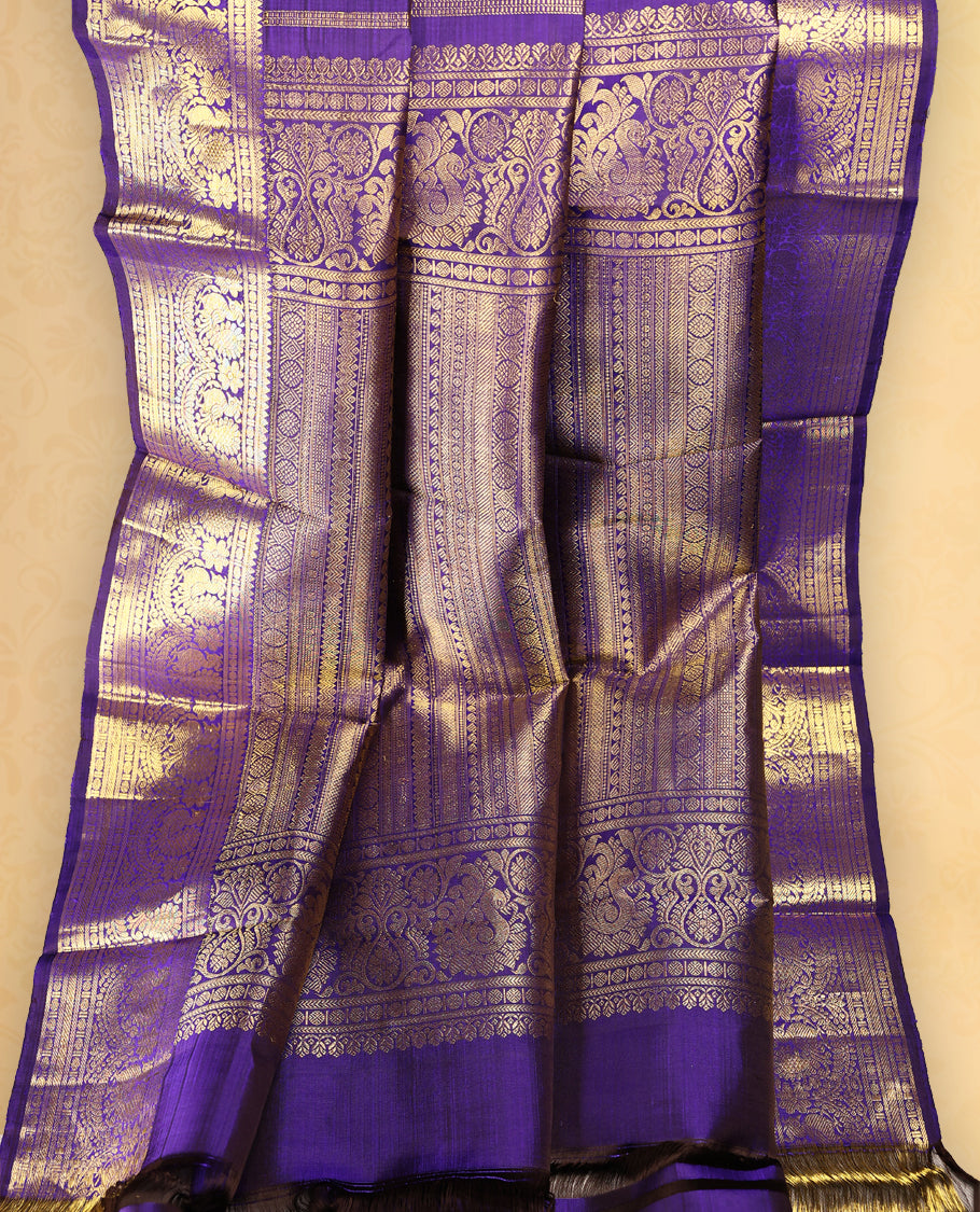 Deep violet colour pure Kancheepuram saree with gold zari Mayoora Chakra motifs on the body, traditional border featuring peacock and floral patterns, grand pallu, and paired with a matching blouse.