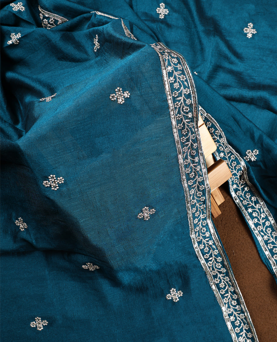 Cookie brown colour churidhar top embellished with intricate silver embroidery, paired with a plain teal bottom and a rich teal dupatta featuring delicate butti work and ornate silver embroidered borders.