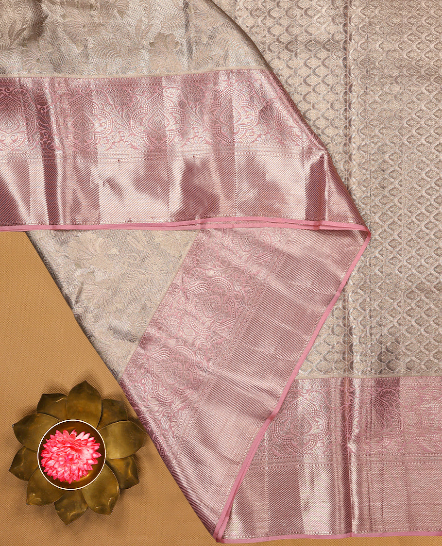 Baby pink Colour Kancheepuram tissue silk saree featuring intricate silver zari floral work on the body, complemented by a contrasting traditional border and a matching blouse.