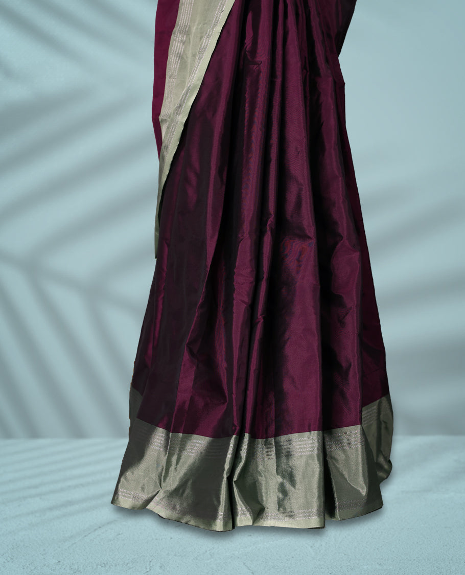 Burgundy Colour semi silk saree features an all over silver zari pattern and a sage green border adorned with traditional temple motifs, paired with a matching blouse.