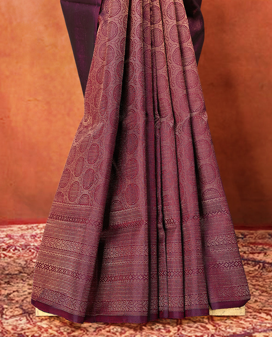 Deep Maroon colour pure Mayuri silk saree featuring finely woven Golden zari motifs across the body, detailed with a subtle geometric self border with intricate texture, with matching blouse